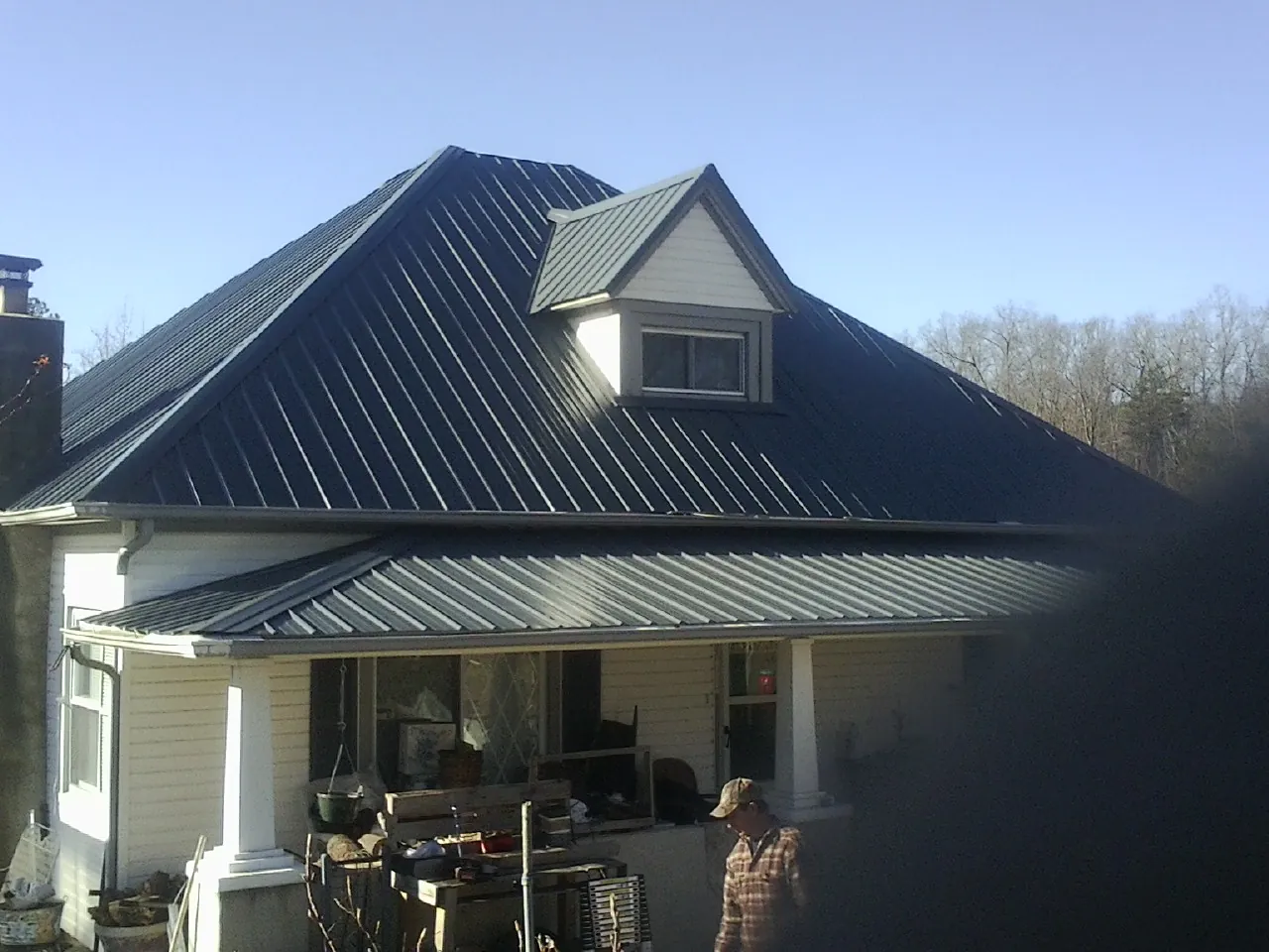 Dark blue standing seam metal roof with a dormer above a front porch in Van Vleck
