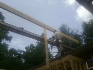 Carpenter setting a ridge beam over a new addition frame — Ice Dam Removal by Roofing Brothers in Van Vleck