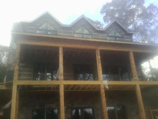Dormers and porch framing on a large log home under construction — Roof Coating work by our crew in Van Vleck
