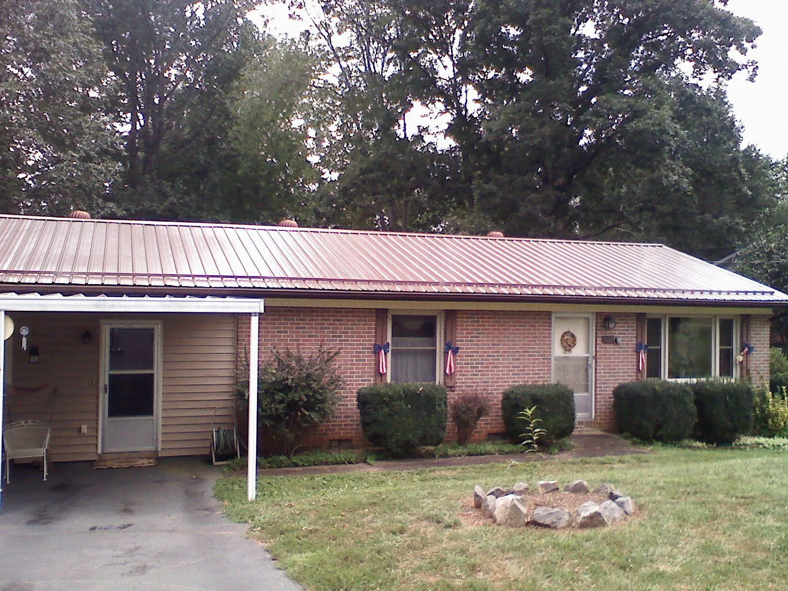 Bronze metal roof and carport on a brick ranch home — Roof Repair work by our crew in Van Vleck