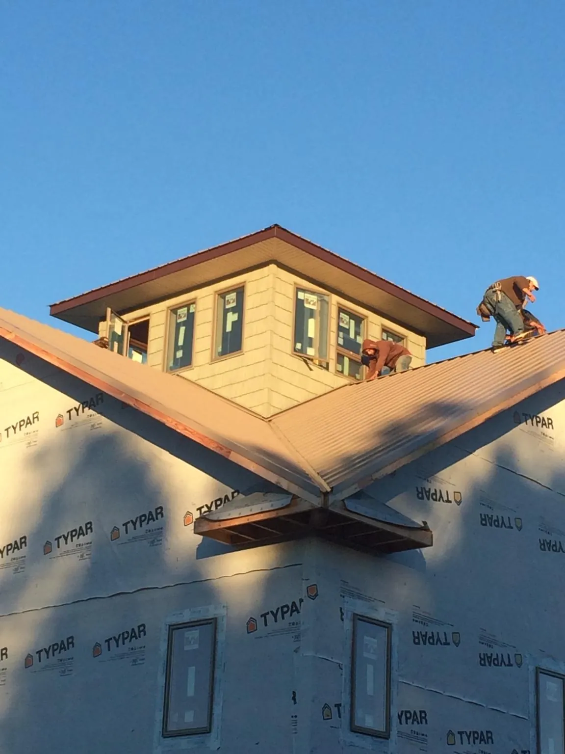 Roofers working around a rooftop cupola on a new metal roof at sunset — Roof Waterproofing in Van Vleck by Roofing Brothers